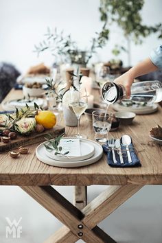 a wooden table topped with plates and glasses