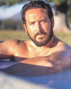 a shirtless man laying on top of a surfboard