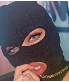 a woman wearing a black mask and chain around her neck