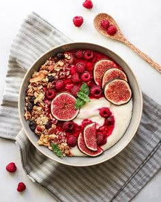 a bowl filled with yogurt, berries and granola on top of a table