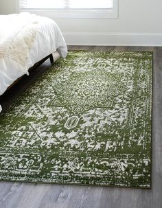 a green and white rug on the floor in front of a bed with a window