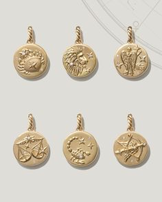 four gold charms with different designs on them, all in different shapes and sizes are shown