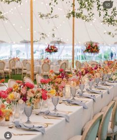 a long table is set up with white linens and floral centerpieces for the tables