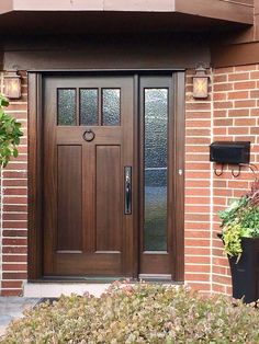 a wooden door with two planters on the side of it next to a brick building