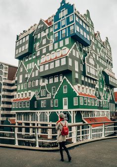 a woman is walking in front of a building with many windows and balconies