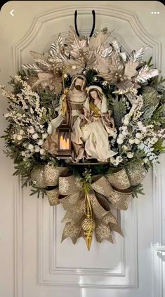 a christmas wreath hanging on the front door with an angel and dove decoration in it