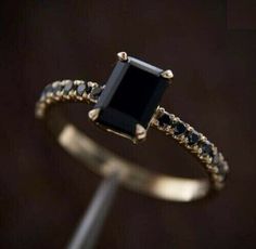 a black diamond ring with white diamonds on the sides and gold band around it's edges