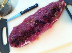 a piece of meat sitting on top of a white cutting board next to a knife