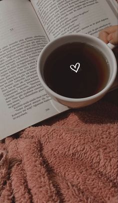 an open book with a heart drawn on it and a cup of coffee in front of it