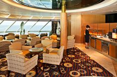 a woman standing in front of a bar on a cruise ship with lots of chairs