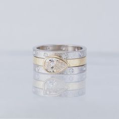 two tone gold and silver wedding rings with white diamonds on the sides, set against a plain background