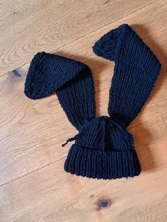 a blue knitted hat and mitten laying on a wooden floor