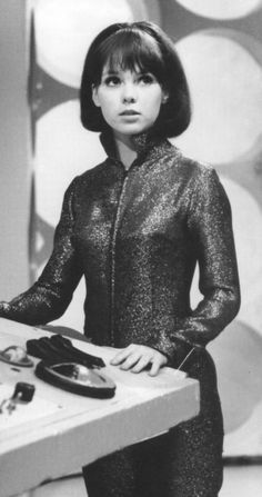 an old photo of a woman standing in front of a table with cell phones on it