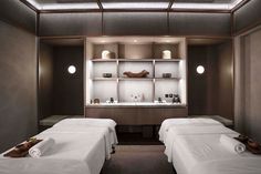 two white beds in a room with shelves and lights on the wall behind them,