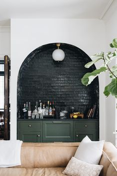 an image of a black brick wall in a living room with green cabinets and white pillows