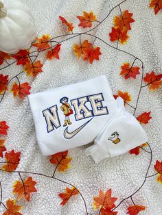 a white shirt with the word nike on it sitting next to fall leaves and pumpkins