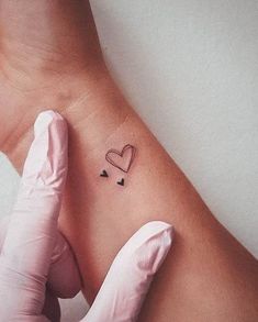 a person wearing gloves and holding their arm with a heart tattoo on it