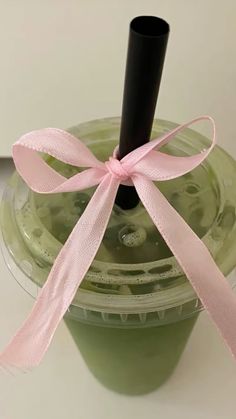 a green smoothie with a pink ribbon on top