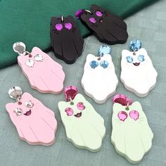 "Ghost Cat earrings are fun for any time of the year. Get a Mixed pair with one of each style, \"Cute\" for two smiling kitties, or \"Spooky\" for two soulless cats with dripping eyes. Current colorways include Black (with purple eyes), White (with light blue eyes), Green (pastel with pink eyes), or Pink (pastel with silver eyes). They are made with mirror and matte acrylics and engraved with details. A cute accessory for any aesthetic. Get them with default studs as pictured, or if you select fishhooks, huggies/leverbacks, or clip-ons the teardrop on top will be replaced.. Dimensions: 1.5 in (38mm) L X 0.97 in (25mm) W 2.0 in (51mm) drop Materials: Acrylic Hypoallergenic Stainless Steel Shipping: All of our jewelry is made-to-order to cut down on waste. Your pieces will be produced and sh Matte Acrylics, Spooky Kitty, Silver Eyes, Light Blue Eyes, Clay Inspo, Silver Eye, Kawaii Jewelry, Spring Pastels, Purple Cat