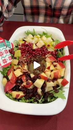 a salad with apples and cranberries in a white bowl on a red table