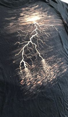 Lightning at sea handpainted with bleach on a black T-shirt. T Shirts Ideas Design Creative, Bleach Black Shirt Design, Dragon Bleach Shirt, Black Bleached Shirt Design, Skull Bleach Shirt, Bleach Tshirt Ideas, Bleached Shirt Art, Painting With Bleach On Fabric, Bleach Designs On Shirts Y2k