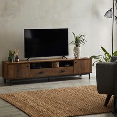 a large flat screen tv sitting on top of a wooden entertainment center in a living room