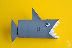 an origami shark with its mouth open on a yellow background that is cut out to look like it has sharp teeth