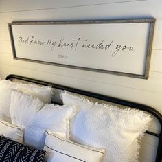 a bed with white pillows and a framed sign above it