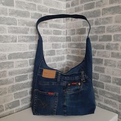 a denim purse sitting on top of a white counter next to a brick wall and floor