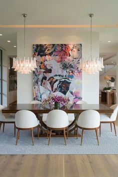 the dining room table is surrounded by white chairs and an abstract painting on the wall