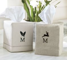 two tissue boxes sitting on top of a counter next to a vase with flowers in it