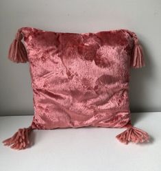 a pink pillow with tassels on it