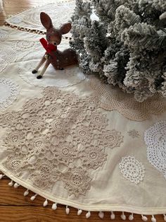 a white doily with a deer figurine sitting on it next to a christmas tree