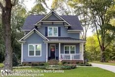 a blue house with white trim and black shutters in the front yard is surrounded by trees