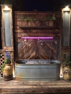 an outdoor hot tub is lit up with purple lights in the background and potted plants around it