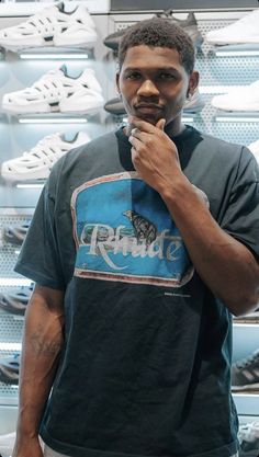 a man standing in front of a wall with shoes on it's shelves and holding his finger to his mouth