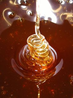 a liquid pouring from a bottle into a bowl filled with oil and other things on the table