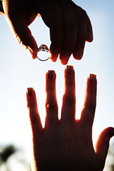 someone is holding their hand up to the sky and there is a ring in it