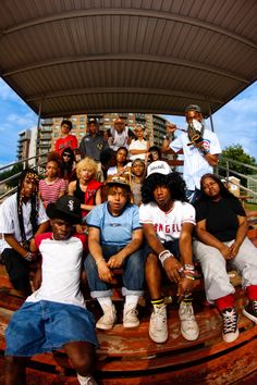 a group of young people sitting on top of a wooden bench next to each other