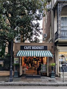 a cafe is on the corner of a street with people sitting at tables under an awning