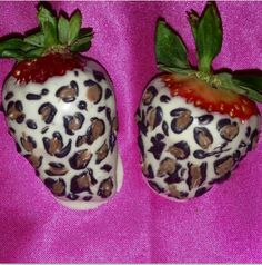 two chocolate covered strawberries are sitting on a pink surface