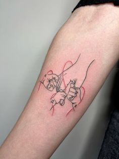 a tattoo on the arm of a woman with two hands holding each other in red ink