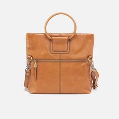 Inspired by our bestselling Sheila satchel, this crossbody has the signature ring handles you know and love. Sheila Foldover Crossbody in Polished Leather  Natural CROSSBODY LARGE Bag in Natural Brown | Hobo® Signature Ring, Signature Rings, Ring Handle, Convertible Bags, Large Wallet, Crossbody Wallet, Small Pouches, Guitar Strap, Wallet Bag