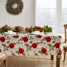 a christmas table with poinsettis and greenery on it, next to a wreath