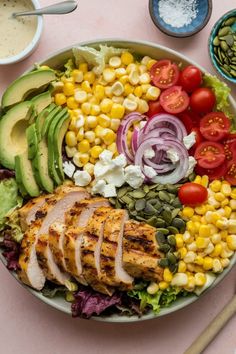 a salad with chicken, avocado, corn and tomatoes