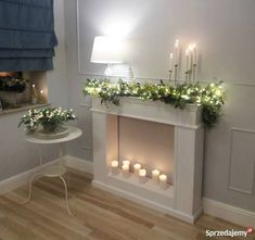 a white fireplace with candles and flowers on it