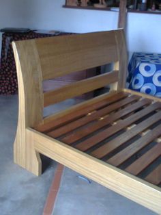 a wooden bed frame sitting on top of a floor next to a blue and white pillow