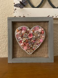 a heart made out of buttons and other things on a wooden table next to a butterfly