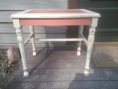 an old pink and white table sitting on top of a porch