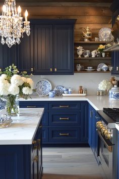 a blue and white kitchen with chandelier hanging from the ceiling over the island